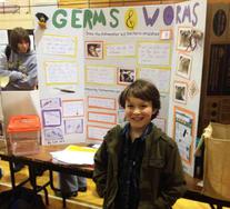 Boy at science fair presenting poster of project "Germs & Worms"!